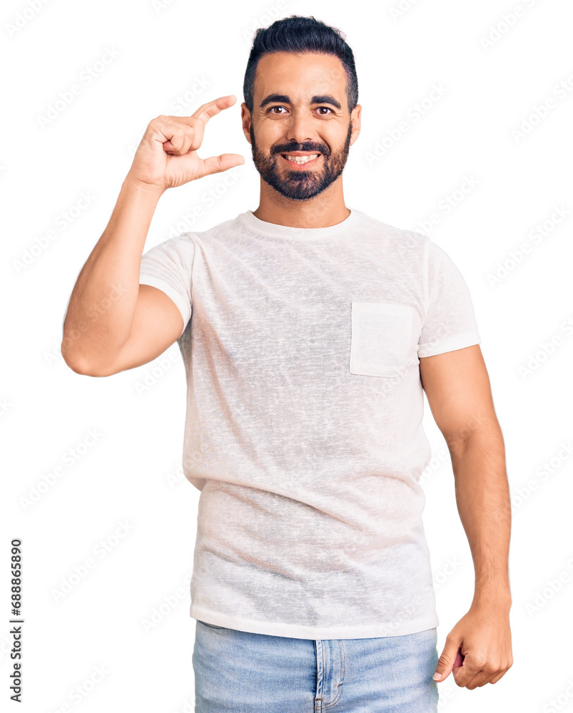 Young hispanic man wearing casual clothes smiling and confident gesturing with hand doing small size sign with fingers looking and the camera. measure concept. Young hispanic man wearing casual clothes smiling and confident gesturing with hand doing small size sign with fingers looking and the camera. measure concept.