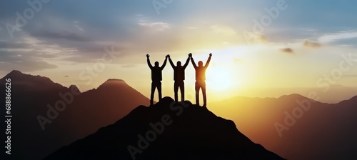 Celebrate victory and success over sunset background, Together overcoming obstacles as a group of three people raising hands up on the top of a mountain. photo