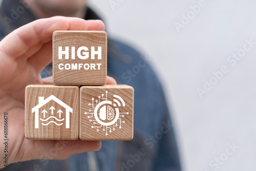 Man holding wooden blocks with icon sees inscription: HIGH COMFORT. Achievement of comfort in everything: life, business, work, home, sleep. Comfortable conditions. High comfort concept.