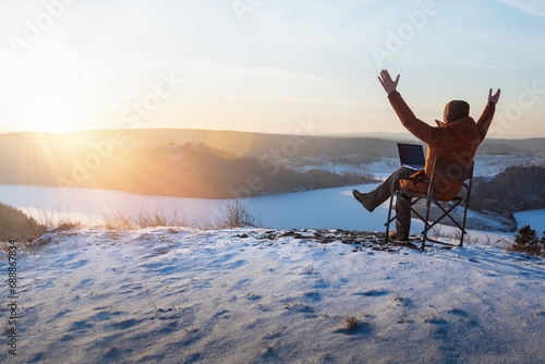 happy man with laptop working outdoor in winter. businessman sitting using computer and  enjoying winter. freedom, remote work concept. photo