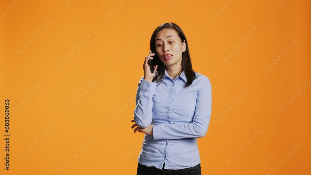 Relaxed person accepting calls in front of the lens interacting with friends on mobile telecoms connection. In the studio, asian girl answers smartphone for remote conversation, chatting. Relaxed person accepting calls in front of the lens interacting with friends on mobile telecoms connection. In the studio, asian girl answers smartphone for remote conversation, chatting.