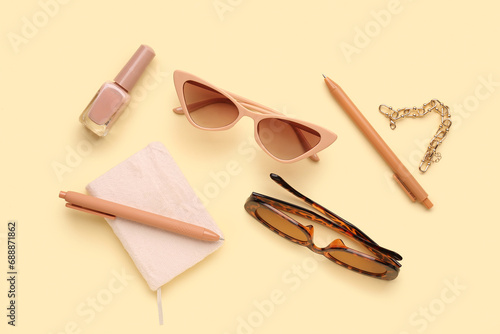 Composition with stylish sunglasses, nail polish, notebook, pens and bracelet on beige background
