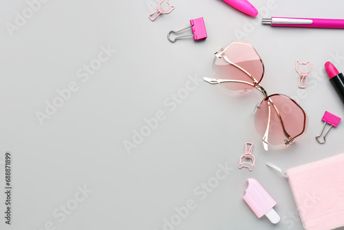 Composition with stylish eyeglasses, stationery and female accessories on grey background