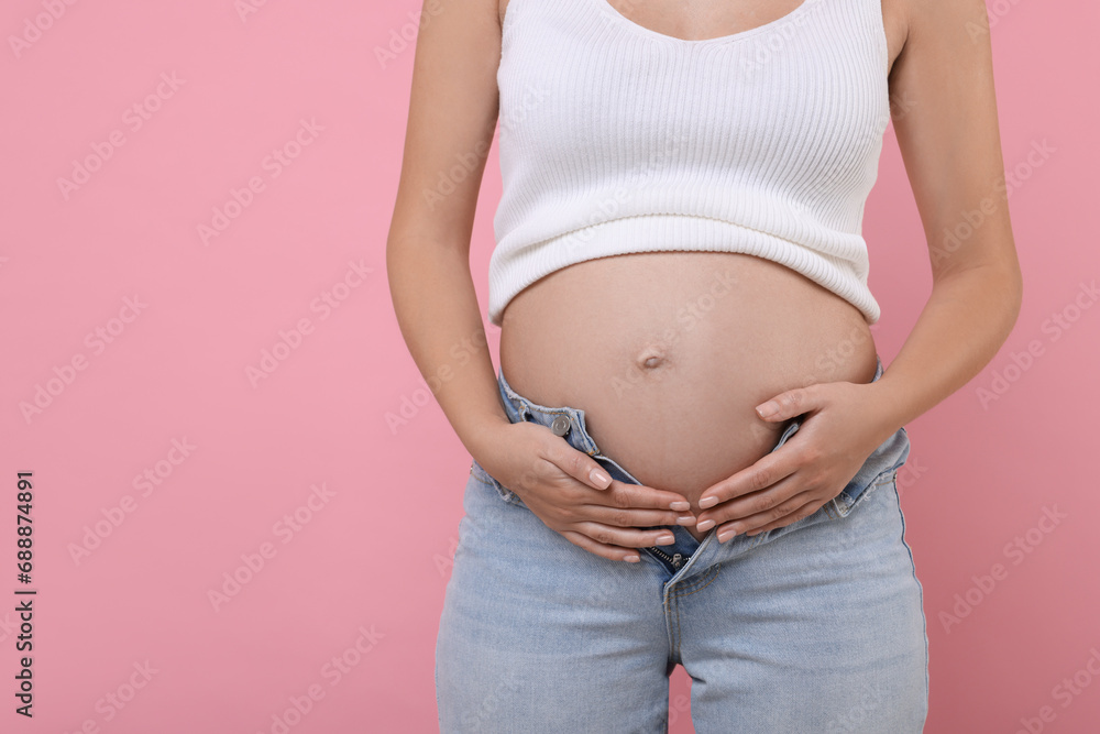 Pregnant woman in jeans on pink background, closeup. Space for text Pregnant woman in jeans on pink background, closeup. Space for text