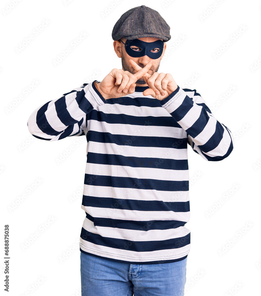 Young handsome man wearing burglar mask rejection expression crossing fingers doing negative sign Young handsome man wearing burglar mask rejection expression crossing fingers doing negative sign