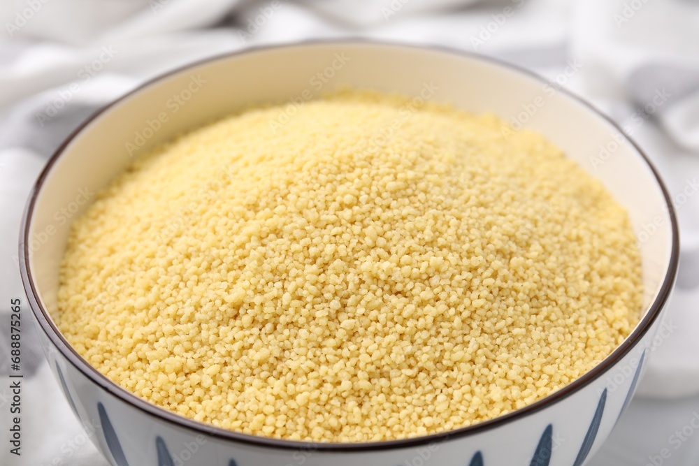 Raw couscous in bowl on table, closeup Raw couscous in bowl on table, closeup