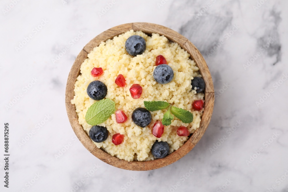 Bowl of tasty couscous with blueberries, pomegranate and mint on white marble table, top view Bowl of tasty couscous with blueberries, pomegranate and mint on white marble table, top view
