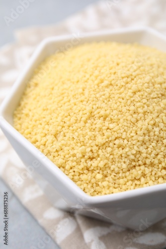 Raw couscous in bowl on table, closeup