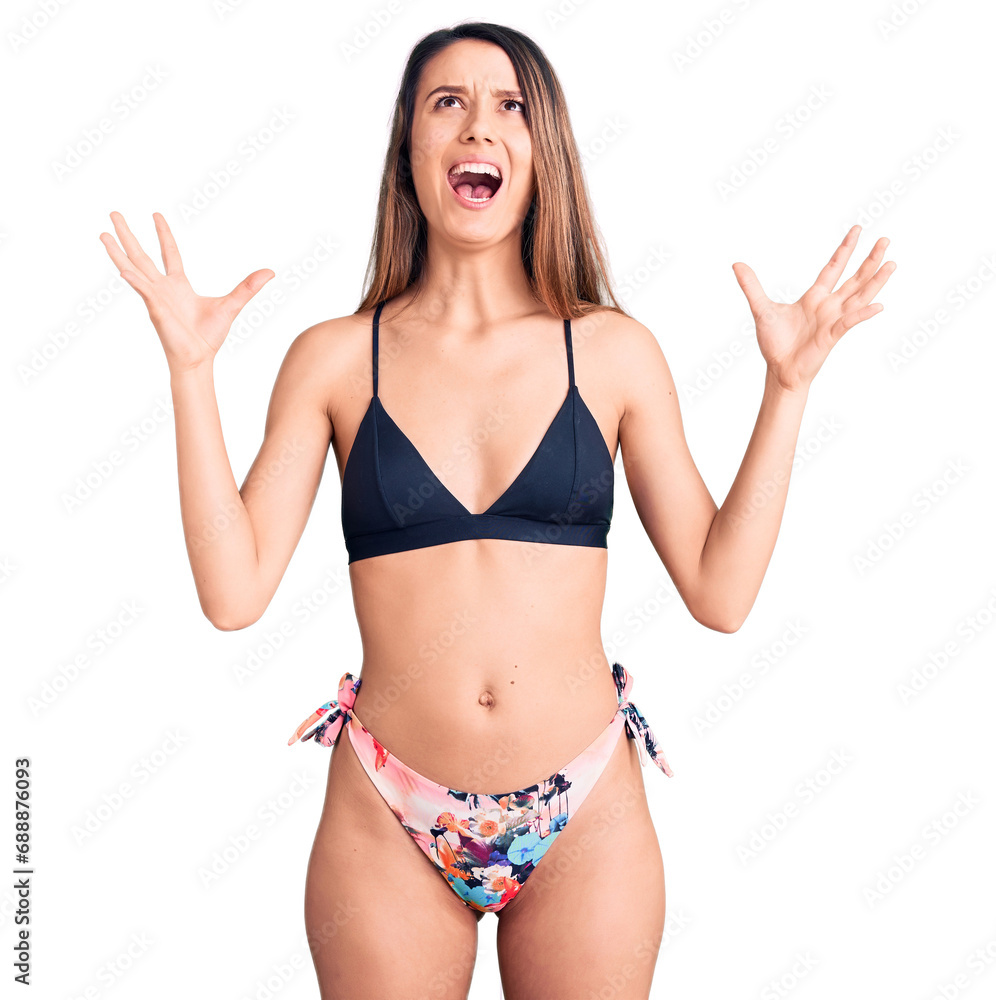 Young beautiful girl wearing bikini crazy and mad shouting and yelling with aggressive expression and arms raised. frustration concept. Young beautiful girl wearing bikini crazy and mad shouting and yelling with aggressive expression and arms raised. frustration concept.