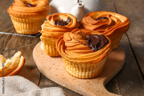 Board of tasty cruffins with chocolate on wooden background photo