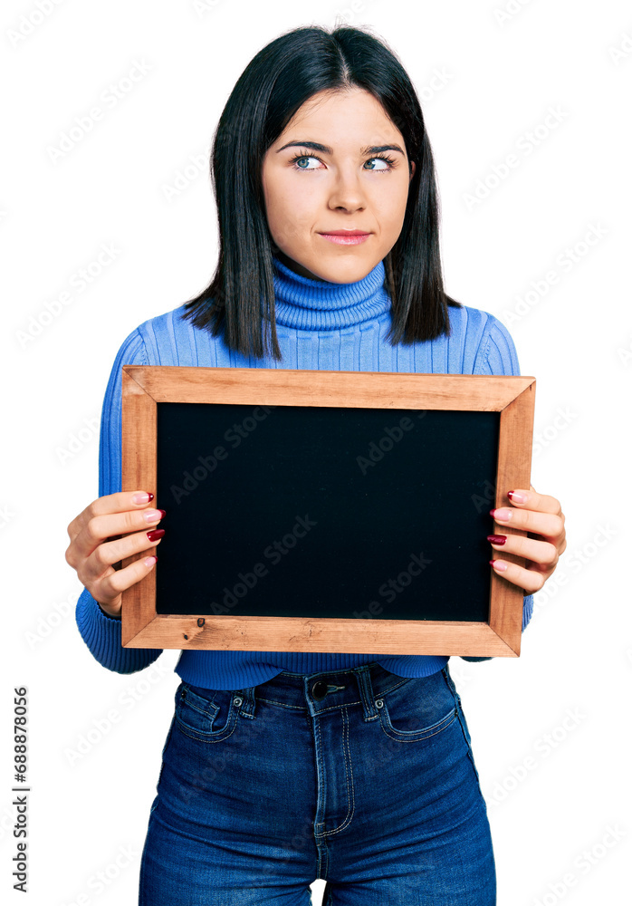 Young brunette woman with blue eyes holding blackboard smiling looking to the side and staring away thinking. Young brunette woman with blue eyes holding blackboard smiling looking to the side and staring away thinking.