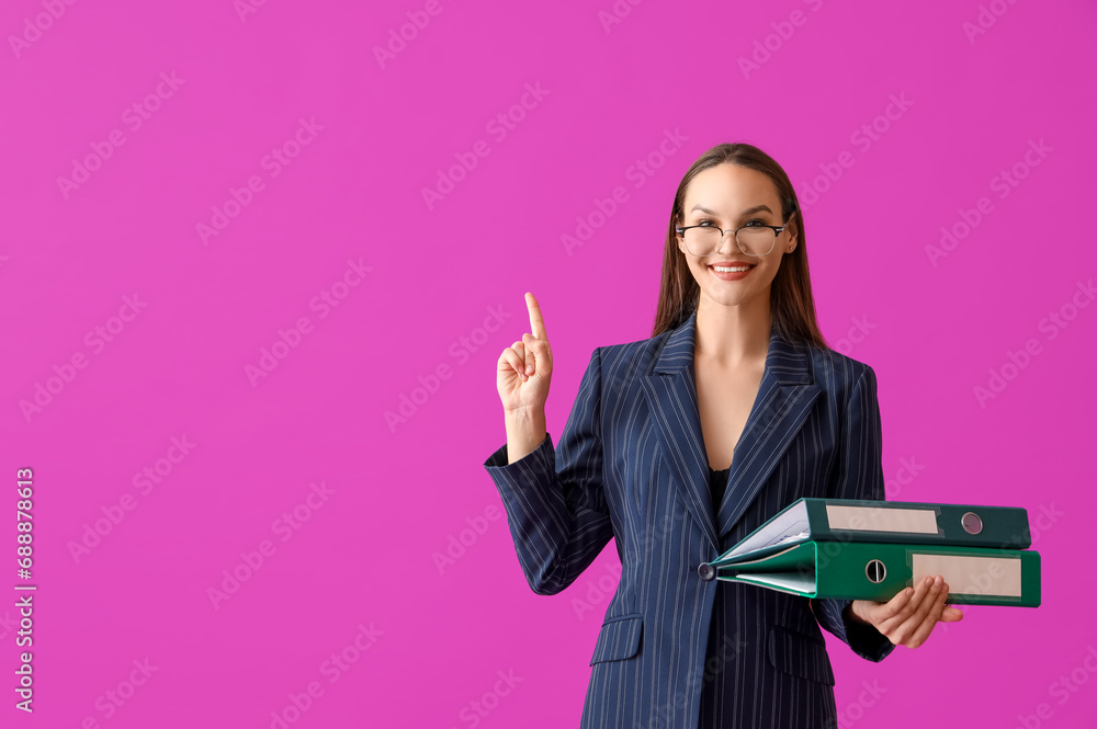 Young businesswoman with document folders pointing at something on purple background Young businesswoman with document folders pointing at something on purple background
