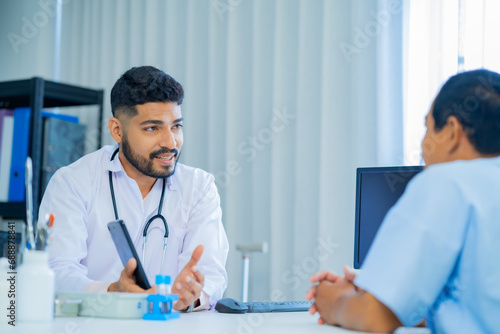 Muslim male and female doctors in medical uniforms was sitting at the patient's examination table and was examining and talking about the patient with a smiling and worried face in hospital.