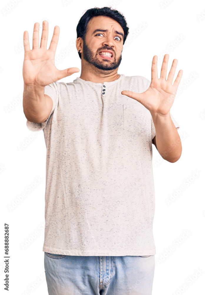 Young hispanic man wearing casual clothes afraid and terrified with fear expression stop gesture with hands, shouting in shock. panic concept. Young hispanic man wearing casual clothes afraid and terrified with fear expression stop gesture with hands, shouting in shock. panic concept.