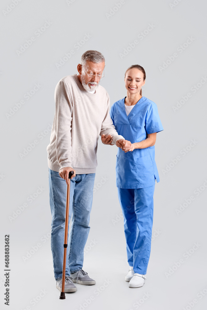 Senior man with walking stick and nurse on light background Senior man with walking stick and nurse on light background