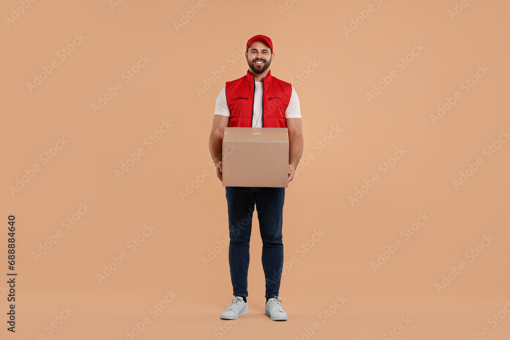 Happy young courier with parcel on light brown background Happy young courier with parcel on light brown background