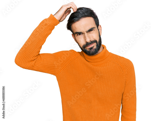 Young hispanic man wearing casual clothes confuse and wonder about question. uncertain with doubt, thinking with hand on head. pensive concept.