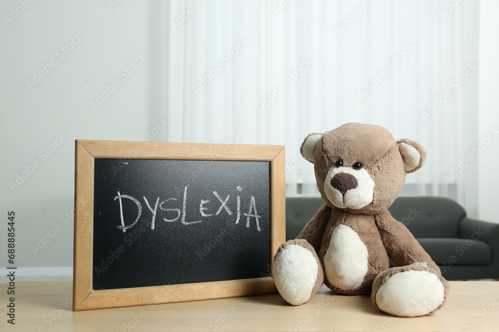 Φωτογραφία Teddy bear and small blackboard with word Dyslexia on wooden table indoors