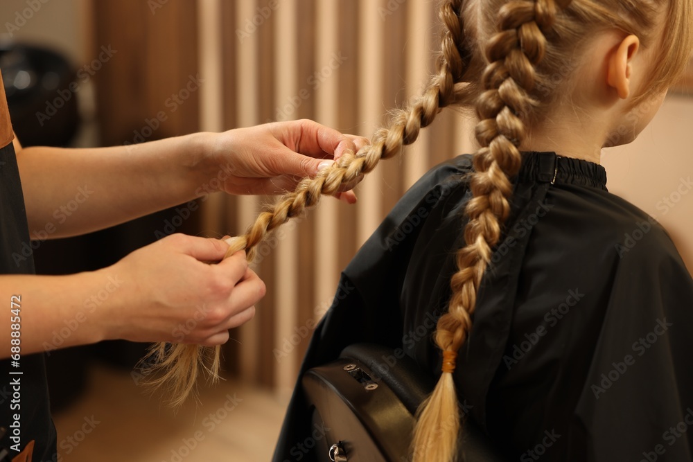 Professional hairdresser braiding girl's hair in beauty salon, closeup - obrazy, fototapety, plakaty 