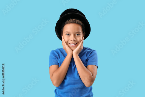 Little African-American boy with hat on blue background