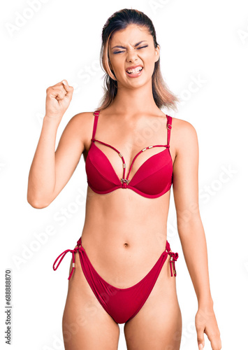 Young beautiful woman wearing bikini angry and mad raising fist frustrated and furious while shouting with anger. rage and aggressive concept. © Krakenimages.com