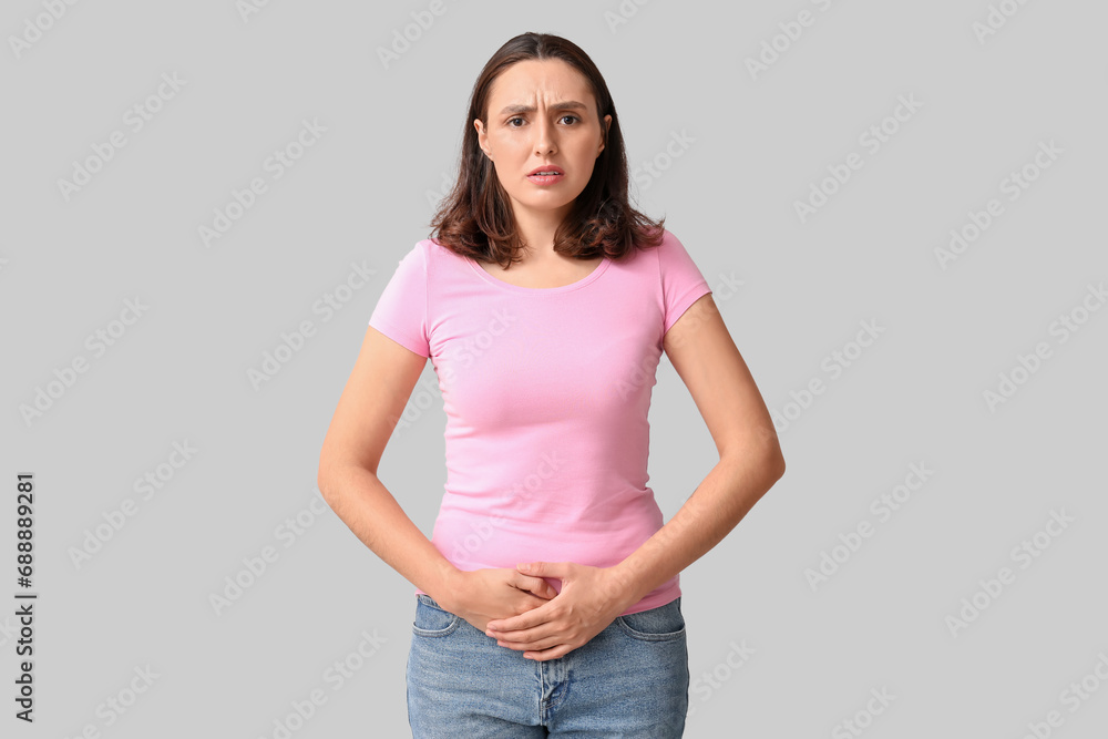 Beautiful young woman suffering from menstrual cramps on grey background Beautiful young woman suffering from menstrual cramps on grey background