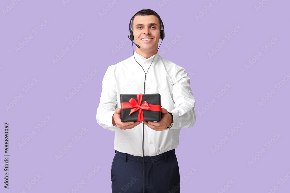 Male technical support agent with gift box on purple background Male technical support agent with gift box on purple background