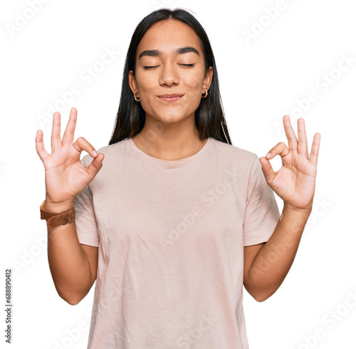 Young asian woman wearing casual clothes relax and smiling with eyes closed doing meditation gesture with fingers. yoga concept.