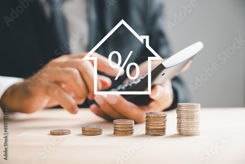 Calculators pressed as hand strategizes home refinance. Desk with house model, buy or rent note. Smart money management to buy property concept. Tax, credit analysis for optimal mortgage payment. photo