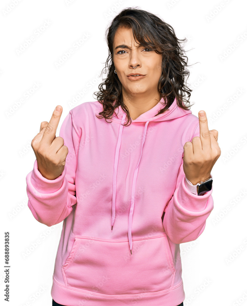Young hispanic woman wearing casual sweatshirt showing middle finger doing fuck you bad expression, provocation and rude attitude. screaming excited Young hispanic woman wearing casual sweatshirt showing middle finger doing fuck you bad expression, provocation and rude attitude. screaming excited
