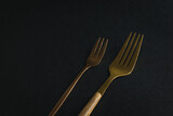 Two metal forks on a black background.