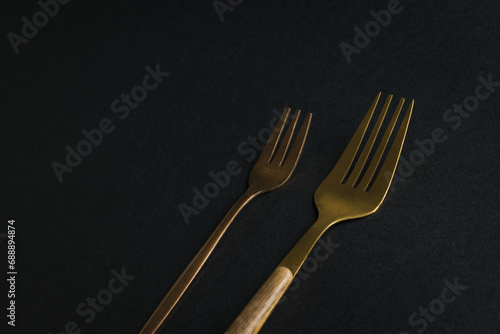 Two metal forks on a black background.