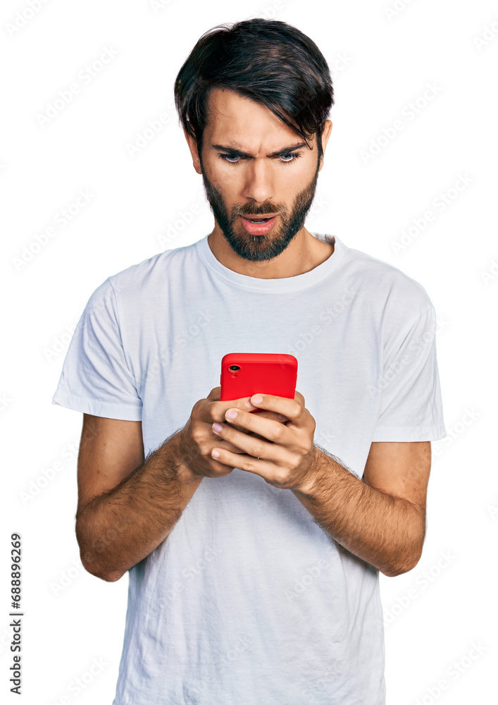 Hispanic man with blue eyes using smartphone typing message in shock face, looking skeptical and sarcastic, surprised with open mouth Hispanic man with blue eyes using smartphone typing message in shock face, looking skeptical and sarcastic, surprised with open mouth