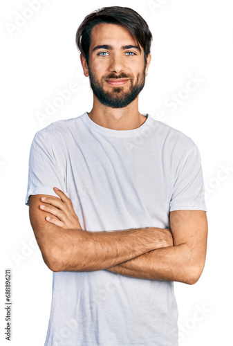Hispanic man with blue eyes wearing casual white t shirt happy face smiling with crossed arms looking at the camera. positive person.