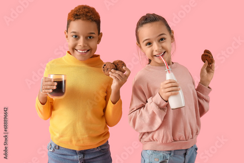 Little children eating cookies with hot chocolate and milk on pink background photo