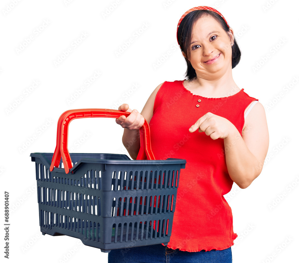 Brunette woman with down syndrome holding supermarket shopping basket smiling happy pointing with hand and finger Brunette woman with down syndrome holding supermarket shopping basket smiling happy pointing with hand and finger