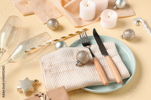 Beautiful table setting for Christmas dinner with decorations on yellow background