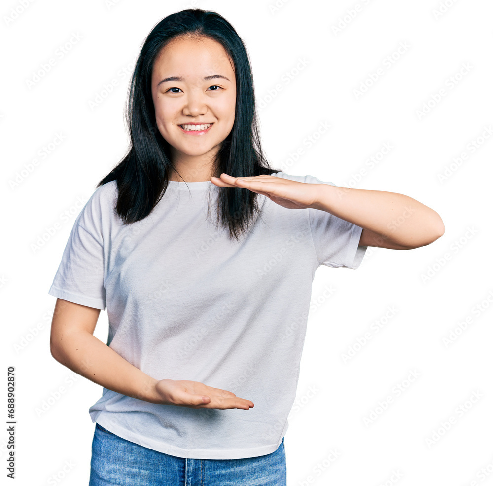 Young chinese woman wearing casual white t shirt gesturing with hands showing big and large size sign, measure symbol. smiling looking at the camera. measuring concept. Young chinese woman wearing casual white t shirt gesturing with hands showing big and large size sign, measure symbol. smiling looking at the camera. measuring concept.
