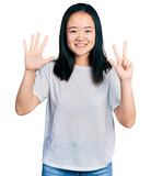 Young chinese woman wearing casual white t shirt showing and pointing up with fingers number eight while smiling confident and happy.