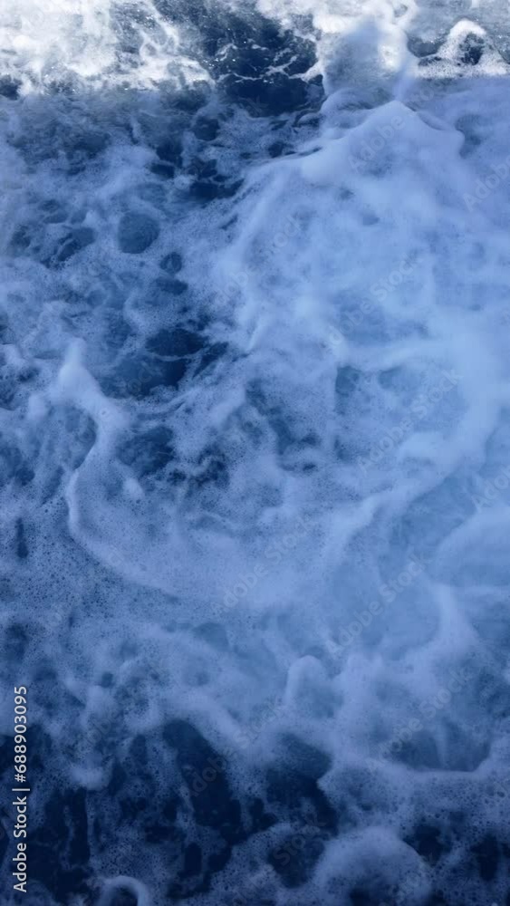 Vertical high-angle view of wake behind large passenger ferry at sea on summer day. White foam trail behind ship created by the motion of ship, slow motion. Concept of vacations and travel. Vertical high-angle view of wake behind large passenger ferry at sea on summer day. White foam trail behind ship created by the motion of ship, slow motion. Concept of vacations and travel.