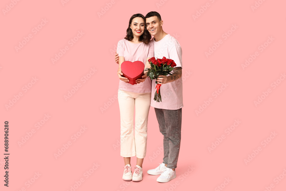Loving young couple with gift box and bouquet of beautiful roses on pink background. Celebration of Saint Valentine's Day Loving young couple with gift box and bouquet of beautiful roses on pink background. Celebration of Saint Valentine's Day