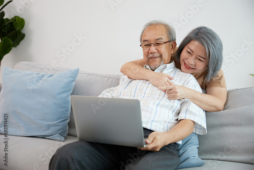 senior couple, elderly man and woman using laptop computer on sofa
