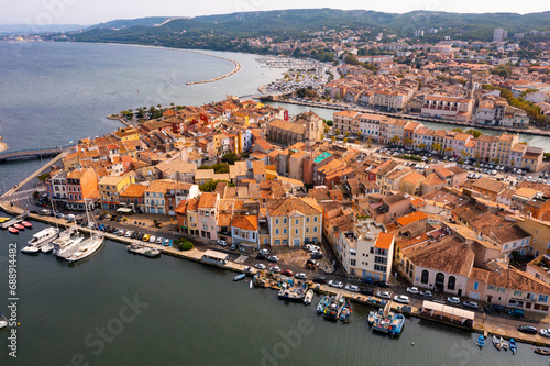 Picturesque aerial view of coastal town of Martigues divided by canals overlooking marina and residential buildings along waterfronts in warm autumn day, France