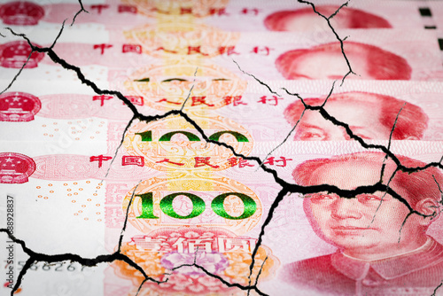 Destruction China economy. Yuans banknotes with cracks.