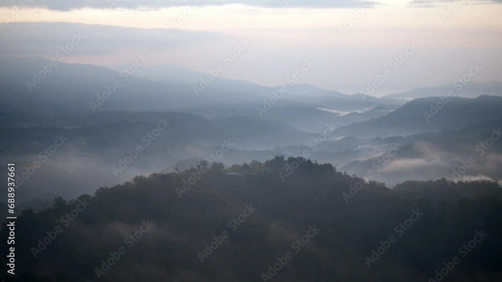 The mist flows through the mountain forest, Sun shining into tropical forest, Mist drifts through mountain ridges in the morning, slow floating fog blowing cover on the top of mountain The mist flows through the mountain forest, Sun shining into tropical forest, Mist drifts through mountain ridges in the morning, slow floating fog blowing cover on the top of mountain