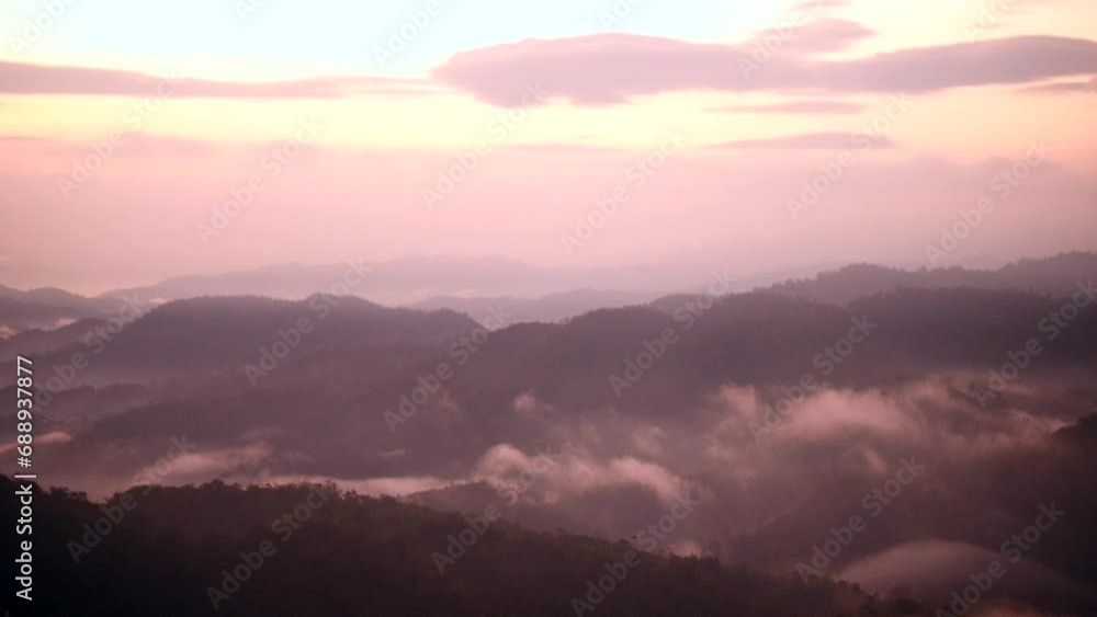 The mist flows through the mountain forest, Sun shining into tropical forest, Mist drifts through mountain ridges in the morning, slow floating fog blowing cover on the top of mountain The mist flows through the mountain forest, Sun shining into tropical forest, Mist drifts through mountain ridges in the morning, slow floating fog blowing cover on the top of mountain