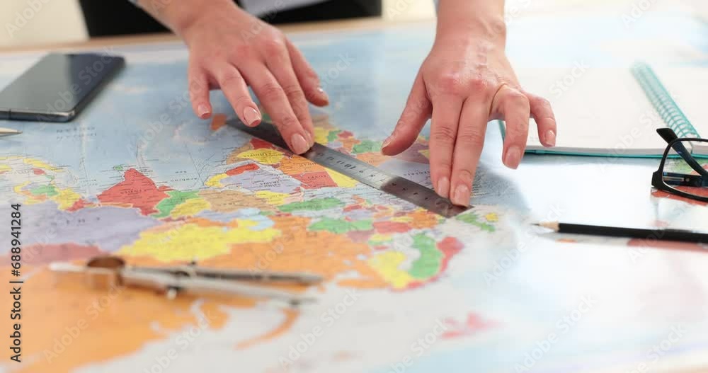 Woman makes markings with ruler while guiding flat map Woman makes markings with ruler while guiding flat map