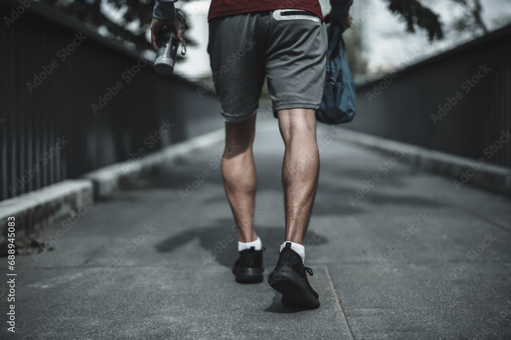 Fototapeta premium A man walking on footbridge in the city center park before cardio workout. Health and Lifestyle in big city life concept.