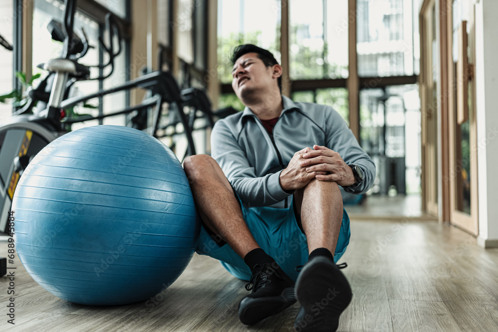 A man use pilates ball and hurt knee at gym. Fitness, gym, workout and lifestyle concept. A man use pilates ball and hurt knee at gym. Fitness, gym, workout and lifestyle concept.