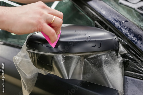 The process of installing PPF on the side mirror. The process of installing PPF on the car. PPF is a polyurethane, protective film that protects the paint from scratches and gravel. Car wrapping. 